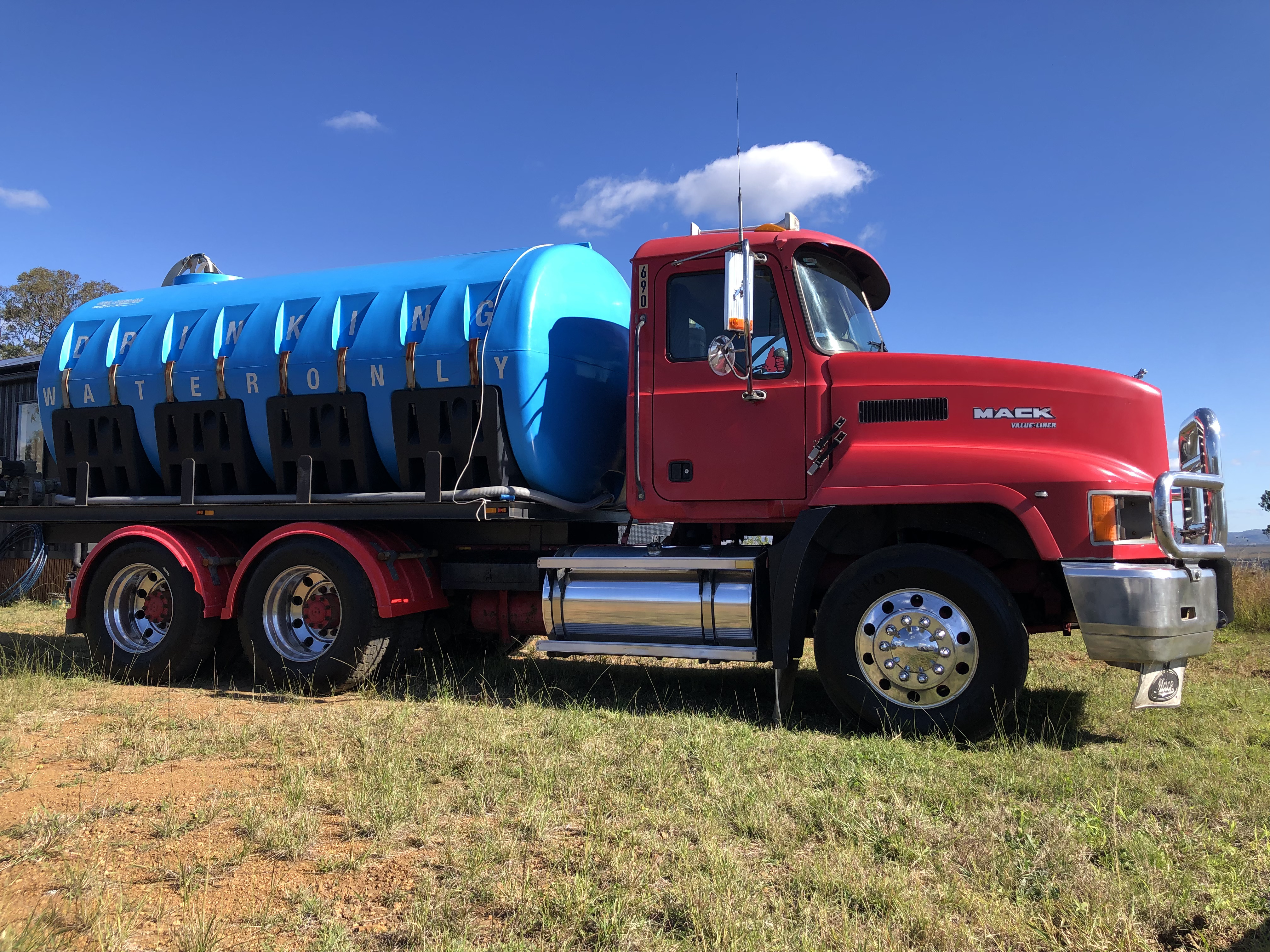 Red Mack water truck with a blue drinking water tank delivering water across Kilcoy and the Somerset region